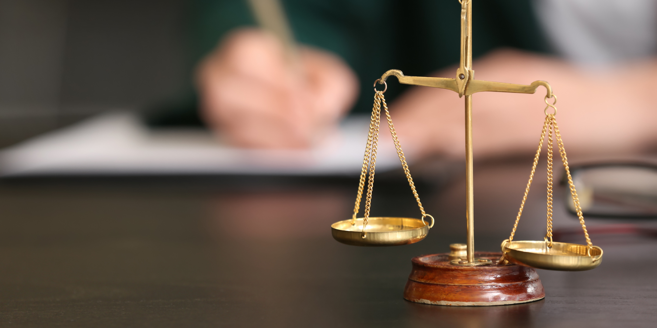 Legal scale with a person writing something in the background