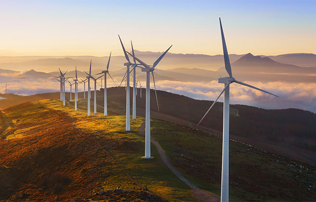 Wind turbines on a hill at dawn.