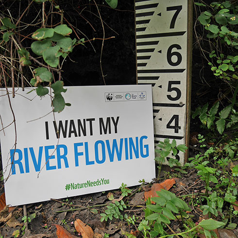 A gauge board in the River Chess with a sign stating 'I want my river flowing'.
