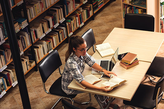 A young academic studying in a library.