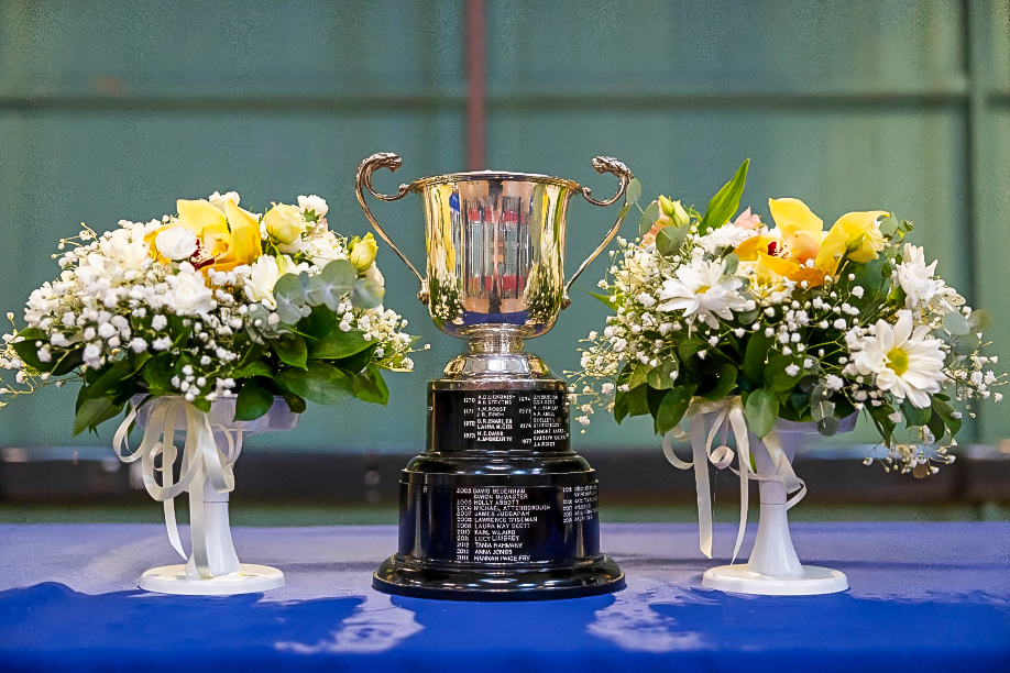 A large trophy on a table between flower bouquets