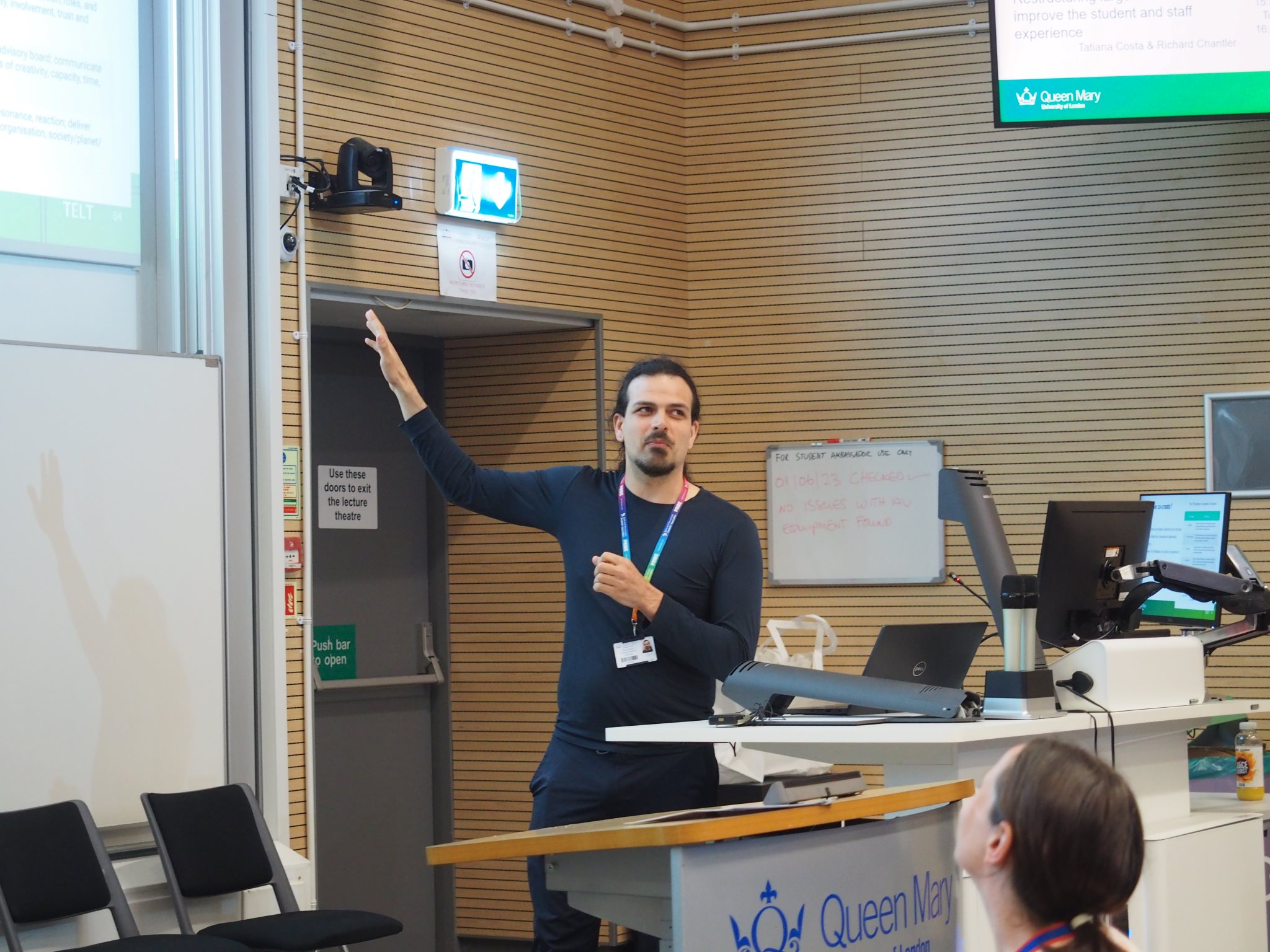 Pedro Elston pointing to the screen while presenting at the front of a lecture theatre